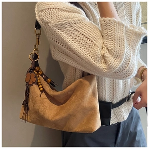 Detail of vintage brown suede hobo bag with wood bead charm and metal hardware hook