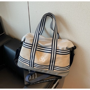 Détail du sac de voyage en toile avec poignées rayées et bandoulière bleu marine