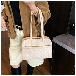Détail du sac cabas beige en daim matelassé avec poignées et une veste marron