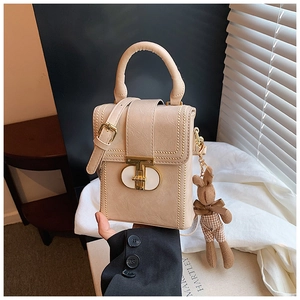 Close-up of beige leather mini bag with gold hardware and a cute rabbit charm