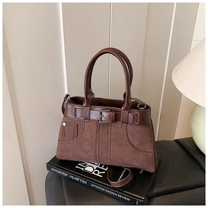 Detail of vintage brown textured bag showing leather stitching and decorative metal buckle