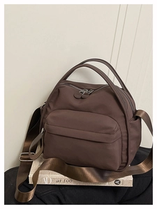 Detail view of brown nylon crossbody bag with dual zippers and adjustable shoulder strap