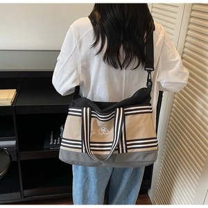 Gros plan d'un grand sac cabas en toile beige avec poignées rayées et logo RB brodé