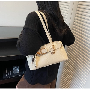 Detail of beige vintage shoulder bag with metal belt buckles and beaded charm accessory