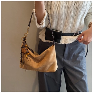 Brown suede dumpling bag with a wooden clover charm shown styled on a model