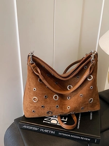 Sac bandoulière en daim marron avec œillets argentés et rivets sur un livre vintage