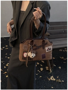 Detail of brown canvas tote bag with apple embroidery and plush dog charm in autumn setting