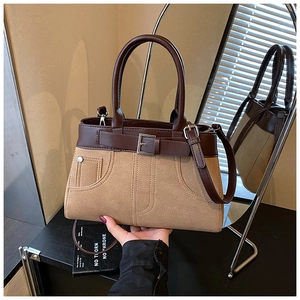 Detail of khaki suede and brown leather stitching with decorative buckle on handbag