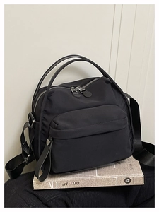 Detail view of black lightweight nylon crossbody bag with dual handles and fabric strap