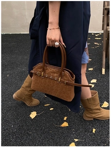 Close-up of brown leopard print suede tote bag with metal buckles on autumn street