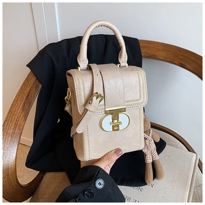 Detail of beige leather bag with gold T-lock and cute plaid teddy bear charm
