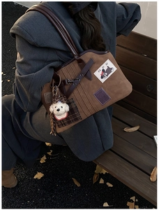Close-up of brown suede tote bag with cartoon dog patch and checkered appliqué details
