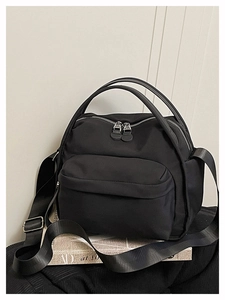 Detail of black nylon crossbody bag with double zippers and adjustable shoulder strap
