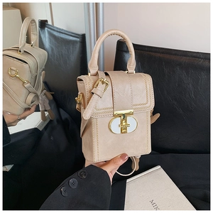 Close-up of beige leather crossbody bag with gold twist lock and cute plush charm