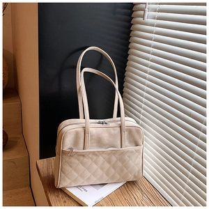 Détail du sac en daim beige avec surpiqûres en losanges sous une lumière naturelle douce