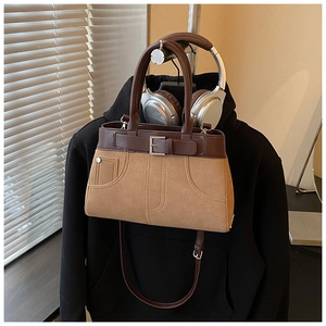Detailed view of retro two-tone handbag with metal rivets and decorative pin buckle strap