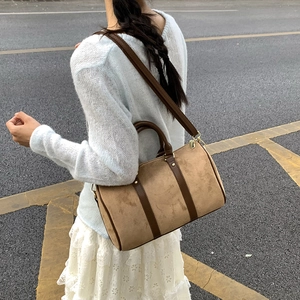 Brown faux suede Boston bag styled with a blue sweater and white skirt outdoors