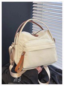 Detail of cream nylon crossbody bag with brown contrast handles and flap pocket