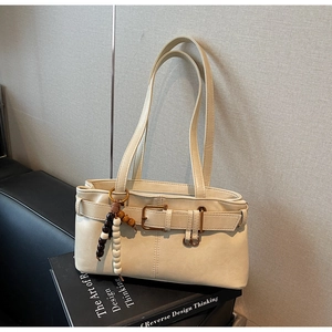 Detail of cream leather handbag with decorative strap and wooden bead charm accessory