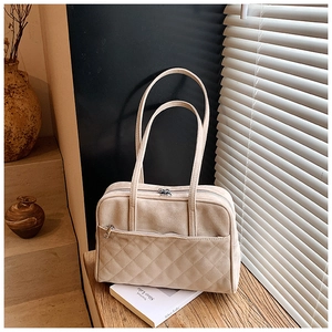 Détail macro du sac cabas en daim beige avec motif matelassé et poches zippées