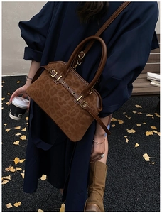 Close-up of leopard print tote bag with gold metal buckle detail in autumn outdoor setting
