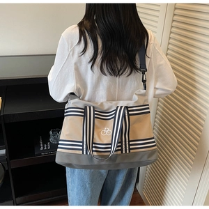 Gros plan d'un grand sac de voyage en toile avec sangles rayées et logo brodé de luxe