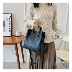 Detail of minimalist black leather bucket bag with cut-out handle and vertical stitching