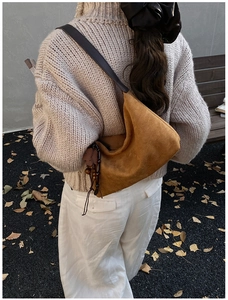 Brown suede hobo bag with leaf charms shown in an outdoor autumn setting