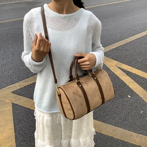 Detail of light brown suede Boston bag with contrast handles and golden hardware