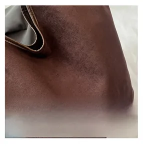 Detailed close-up of dark brown suede texture and leather stitching on bucket bag