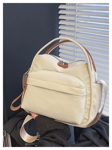 Detail of off-white nylon tote bag with contrasting brown handle and front zipper pocket