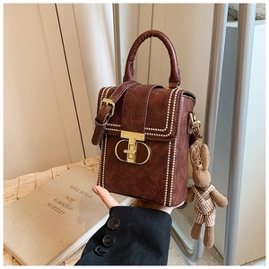 Close-up of vintage brown leather handbag with pearl edge and knit bunny charm