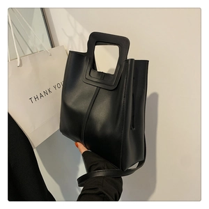 Close-up of black PU leather bucket bag featuring a square cutout handle and fine matte texture