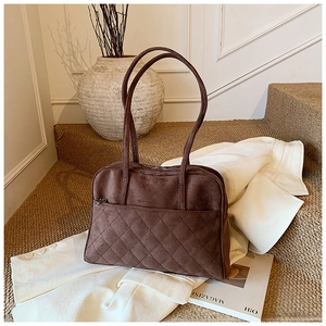 Gros plan d'un sac bandoulière en daim marron avec surpiqûres losanges et longues anses