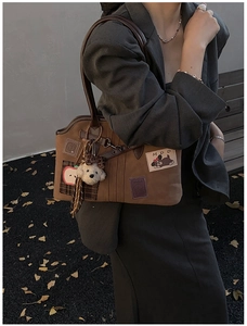 Detail of suede tote bag with apple embroidery, MDD patch, and plush bear charm