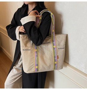 Detailaufnahme der großen Canvas-Tragetasche mit bunten Jacquard-Gurten und Markenlogo