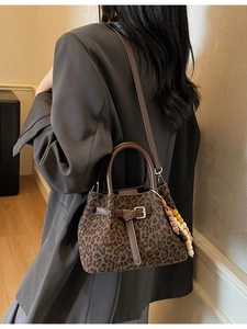 Retro leopard print bucket bag with leather handles and beaded charm shown on model
