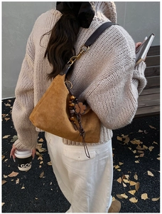 Close-up of brown suede shoulder bag with vintage leather strap and floral charm detail