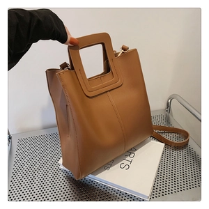 Detail view of large brown bucket bag with unique square cutout handle and shoulder strap