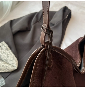 Detail of thin leather shoulder strap tied to a dark brown suede bucket tote bag