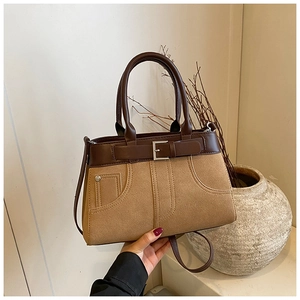 Detail of vintage tote bag with buckle accents and utility pockets on a textured brown surface
