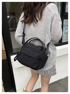 Detailed view of lightweight black nylon handbag with adjustable strap on a model
