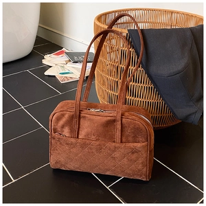 Détail d'un sac à main en daim marron avec matelassage en losanges et poche zippée avant