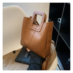 Detail of caramel brown bucket bag with square cutout handle and contrast stitching
