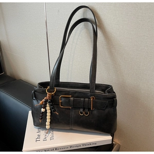 Close-up of black retro baguette bag featuring metal buckle and wooden bead charm