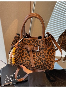 Women's leopard print bucket bag with brown leather handles and colorful beaded charm