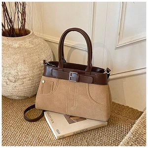 Detailed close-up of brown leather and khaki suede contrast stitching on a handbag