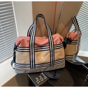 Détail du sac de voyage multicolore avec poignées rayées bleues et logo sur nylon