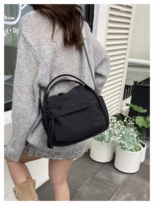 Street view of a black nylon crossbody bag with adjustable strap on a female model
