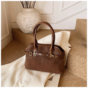 Detail of leopard print tote bag featuring matte texture and metallic hardware accents